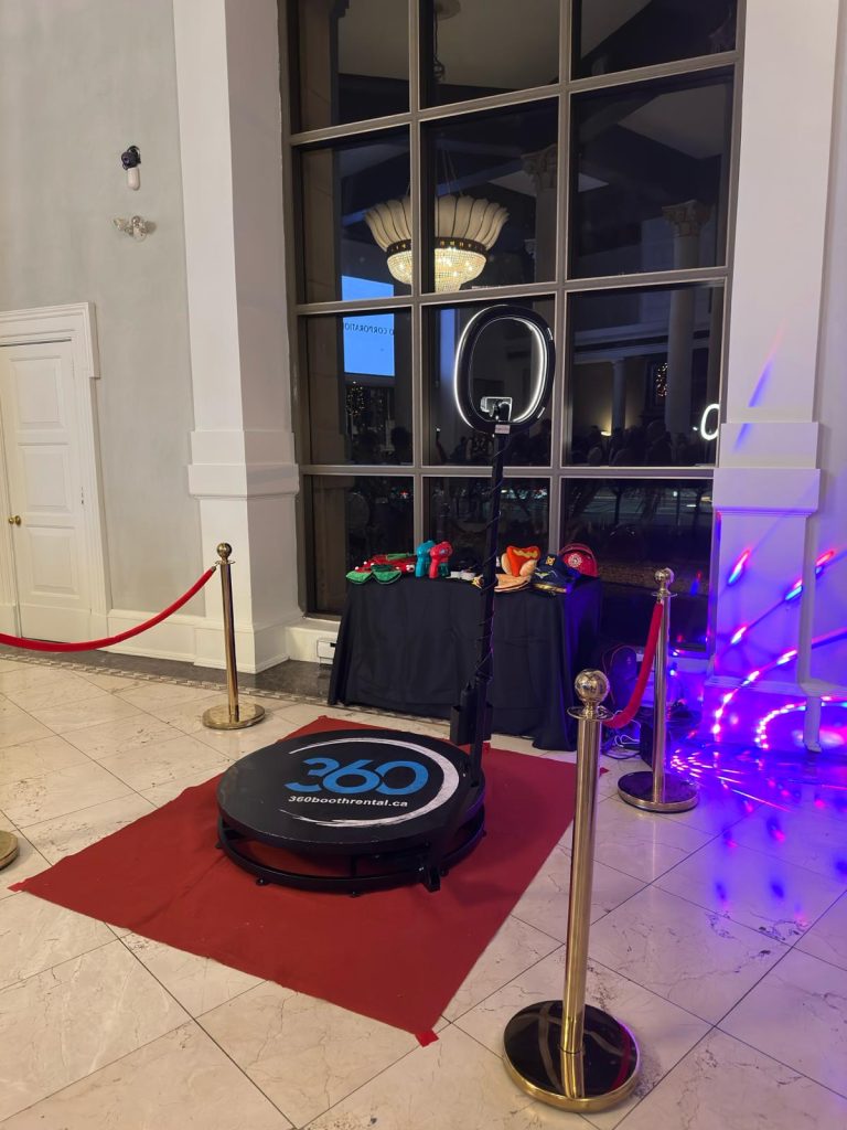 360 video booth in Gravenhurst, seated upon a red carpet and surrounded by stanchions. Props are in the background.